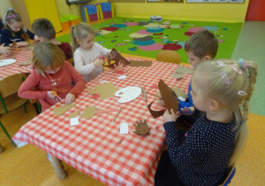 Czwórka dzieci wycina z papieru szablon dłoni.